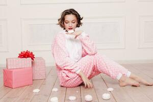 fofa pequeno menina dentro pijama com doces sentado em a chão foto