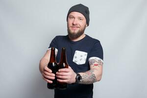 brutal barbudo masculino com tatuado braço bebidas uma Cerveja a partir de uma garrafa. foto