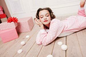 fofa pequeno menina dentro pijama com doces sentado em a chão foto