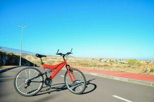 uma vermelho bicicleta é estacionado em a lado do a estrada foto