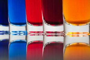 pequeno óculos preenchidas com colorida água estão ordenadamente arranjado em a isolado branco fundo foto