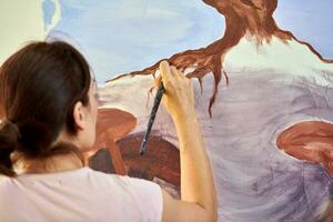 menina artista mão detém pintura escova e desenha abstrato natureza panorama em tela de pintura foto