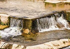 uma cascata dentro uma rio com pedras e água foto