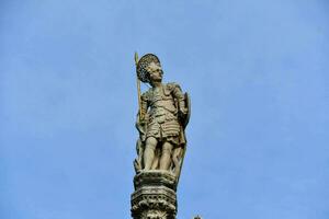 uma estátua do uma homem segurando uma espada em topo do uma construção foto