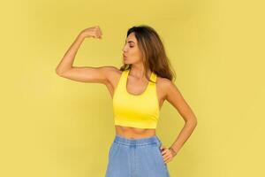 estúdio foto do bonita morena mulher dentro esportivo equipamento posando em amarelo fundo.