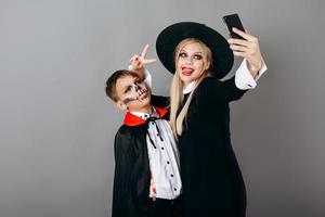 mãe e filho em fantasias mostrando gesto de vitória e fazendo selfie no fundo do estúdio foto