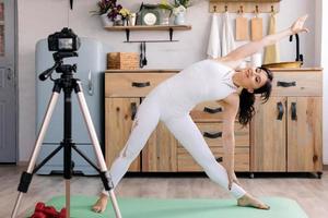 linda garota em roupas esportivas faz ioga e grava um vídeo para seu blog foto