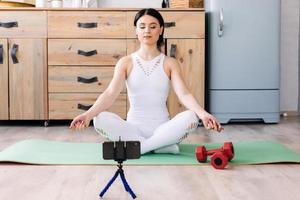 menina está fazendo meditação e exercícios no tapete dentro de casa foto