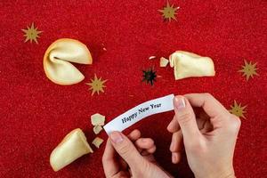 biscoitos da sorte em mãos com os cumprimentos de ano novo foto