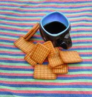 uma copo do chá com café e biscoitos. Preto e azul copo. foto