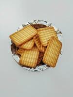 trigo biscoitos dentro a aço prato com branco fundo. indiano biscoitos popularmente conhecido Como chai bolacha dentro Índia foto