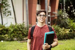 jovem hispânico aluna sorridente feliz vestindo uma mochila às a universidade campus. foto