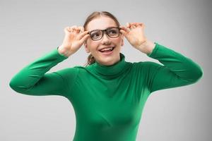 menina sorridente de óculos posando no estúdio e parece felizmente de lado. - imagem foto