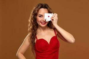 bonita jovem cabelos castanhos mulher dentro vermelho coquetel vestir segurando par do ases e sorridente foto