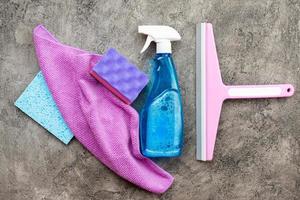 acessórios domésticos, spray de lavagem, esponja, pano e escovas de lavagem sobre um fundo de gesso decorativo cinza. foto