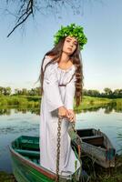 jovem mulher com flor guirlanda em dela cabeça, relaxante em barco em rio às pôr do sol. conceito do fêmea beleza, descansar dentro a Vila foto