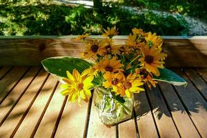 uma vaso do amarelo flores em uma de madeira mesa foto