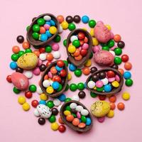 ovos de páscoa de chocolate e bombons no fundo rosa com espaço de cópia foto