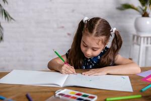 inspirado pequeno menina às a mesa desenhar com giz de cera ou Faz casa trabalhos foto