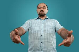 fechar-se retrato do uma moreno meia idade homem com barba, vestido dentro uma luz xadrez camisa e posando contra uma azul fundo. foto