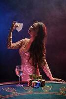 morena menina com uma perfeito Penteado e brilhante Maquiagem é posando com jogando cartões dentro dela mãos. cassino, pôquer. foto