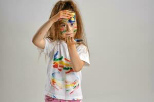 pequeno menina dentro branco pintado camiseta, com colori face é jogando com uma esponja encharcado dentro pintar. isolado em branco. fechar-se. foto