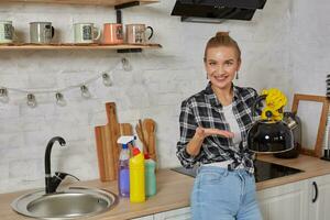 doméstico serviço e serviço de limpeza conceito, feliz Loiras senhora limpeza cozinha chaleira. foto