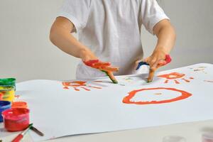 pequeno artista dentro branco camiseta em pé às mesa com que homem e colorida tintas, pintura em isto com dela mãos. isolado em branco. fechar-se. foto