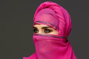 fechar-se tiro do uma jovem encantador mulher vestindo a Rosa hijab decorado com lantejoulas. árabe estilo. foto