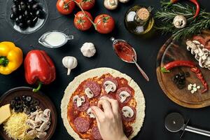 mãos do padeiro adicionando ingredientes para dentro pizza durante pizza preparação às cozinha foto