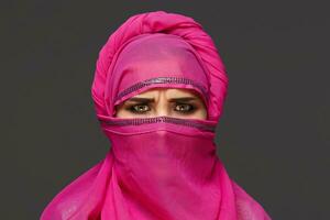 fechar-se tiro do uma jovem encantador mulher vestindo a Rosa hijab decorado com lantejoulas. árabe estilo. foto