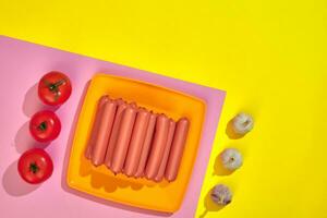 pilha do fino salsicha salsichas com tomates em prato em Rosa e amarelo fundo foto