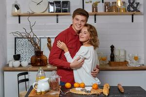 feliz jovem adorável casal em cozinha abraçando cada outro. elas apreciar gastos Tempo juntos foto