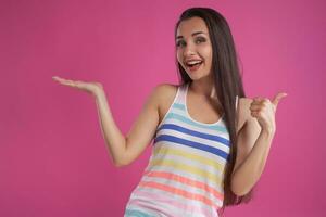 morena mulher com grandes cabelo, vestido dentro colorida listrado camisa, posando contra Rosa estúdio fundo. sincero emoções. fechar-se. foto