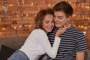 feliz amoroso casal relaxante em cama às lar, jovem mulher tocante sorridente bonito homem face foto