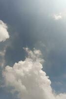 brilho branco nuvem em pálido azul céu fundo com Sol clarão, dramático humor papel de parede. foto