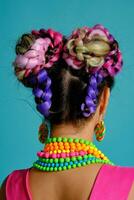 adorável menina com uma multicolorido tranças Penteado e brilhante inventar, posando dentro estúdio contra uma azul fundo. foto