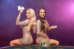 lindo meninas com uma perfeito penteados e brilhante Maquiagem estão posando em pé às uma jogos de azar mesa. cassino, pôquer. foto