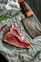 cru seco envelhecido t-bone bifes para grade com fresco ervas e cutelo foto