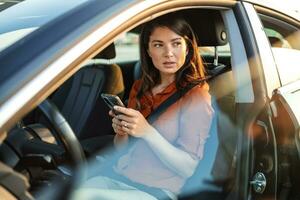 retrato do uma jovem mulher mensagens de texto em dela Smartphone enquanto dirigindo uma carro. o negócio mulher sentado dentro carro e usando dela Smartphone. fêmea motorista e telefone tela foto