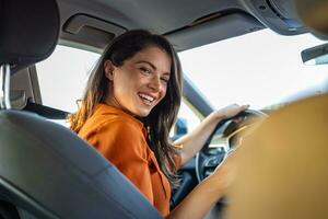 jovem mulher sentado em uma motorista assento dentro a carro e olhando às Câmera sobre a ombro. retrato do agradável fêmea com positivo expressão, ser satisfeito com inesquecível viagem de carro. foto