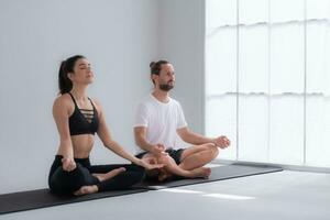 jovem casal meditando dentro lótus pose em exercício esteira às lar, ioga exercício conceito foto