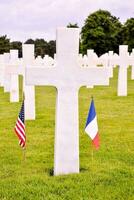 uma Cruz e americano e francês bandeiras dentro uma cemitério foto