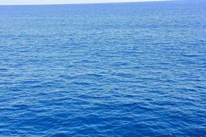 a oceano é azul e calma com uma barco dentro a distância foto