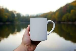 mão segurando uma branco caneca em a fundo do uma montanha panorama. foto