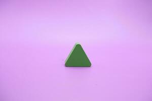 verde de madeira forma brinquedo. triângulo em roxa fundo foto