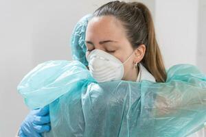 médico e enfermeira abraçando às hospital e brigando vestindo protetora ternos e máscaras.. médicos estão Heróis. ótimo equipe. comunhão. foto