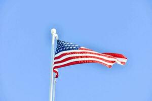 a americano bandeira vôo dentro a vento contra uma azul céu foto