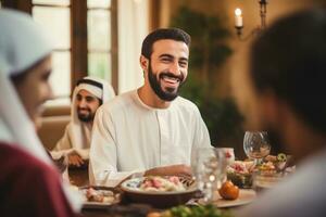 ai gerado bonito árabe homem é falando para dele família e sorridente enquanto tendo jantar às lar, bonito árabe homem falando para alegre multicultural muçulmano família durante jantar, ai gerado foto