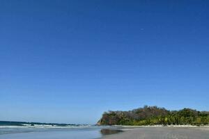 uma de praia com uma azul céu e uma Claro oceano foto